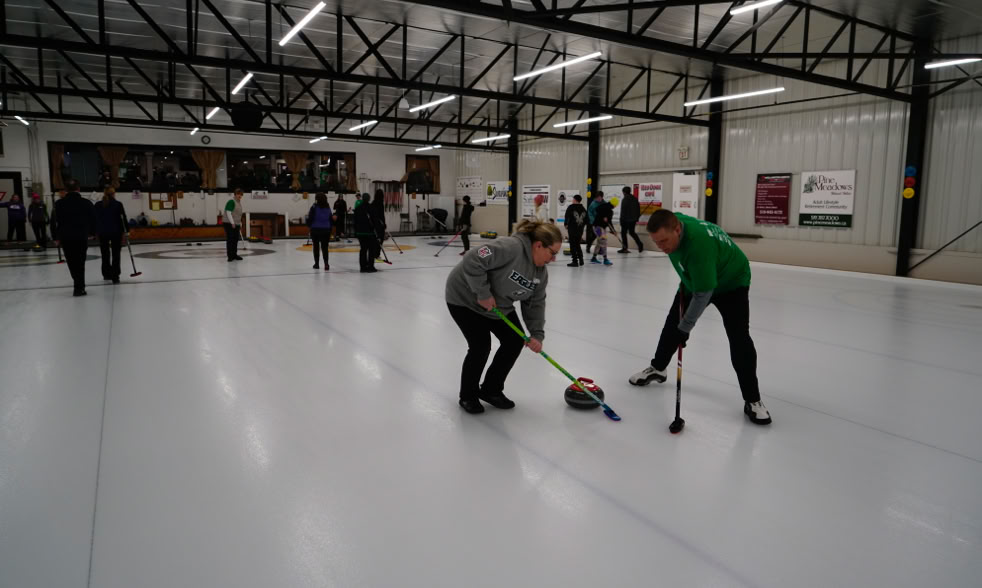 Two team members sweeping in front of rock at 2024 Curl For A Cause.