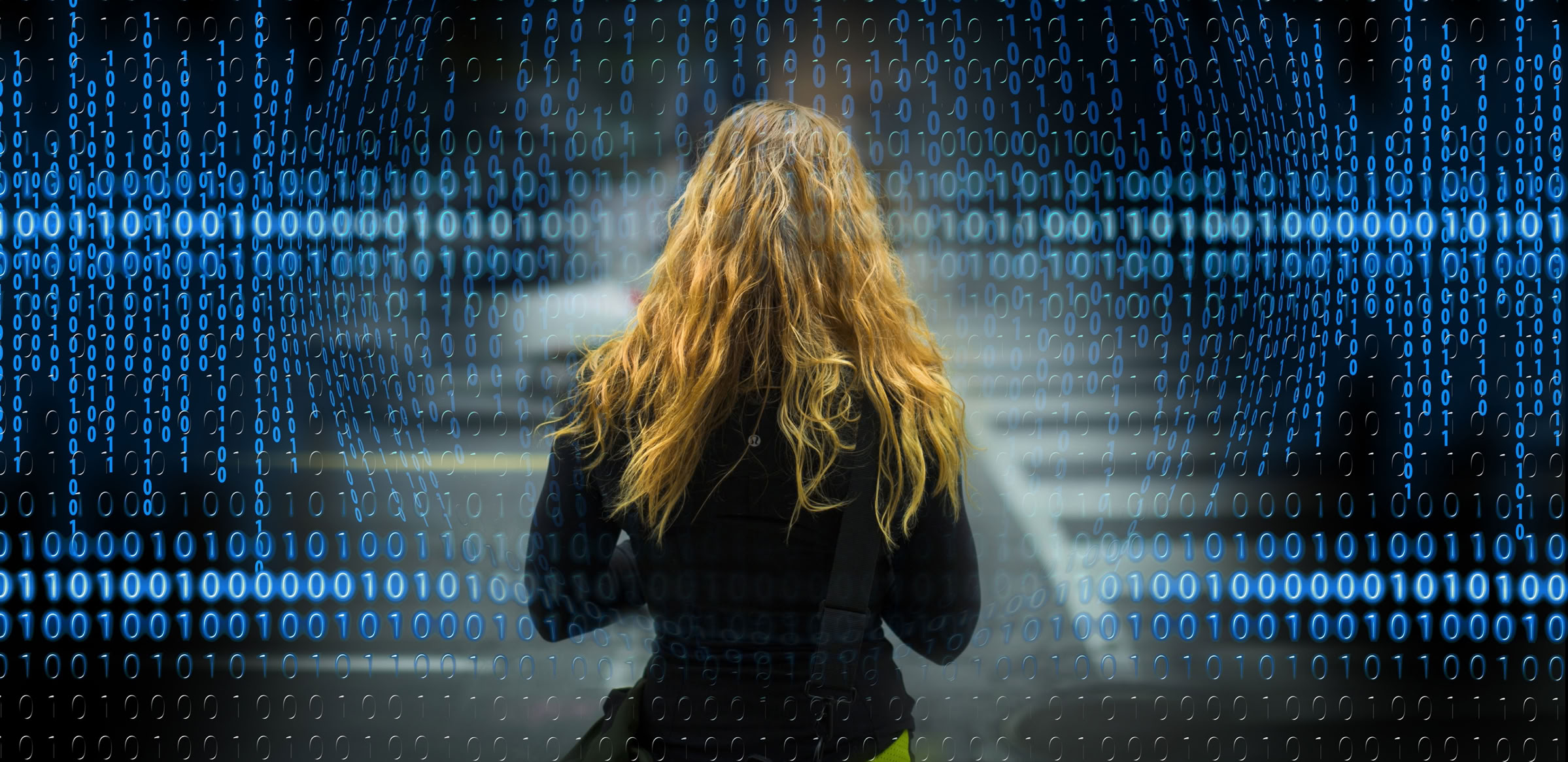 Woman staring at a screen full of binary numbers