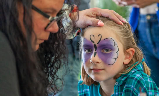 Young girl getting a butterfly painted on her face