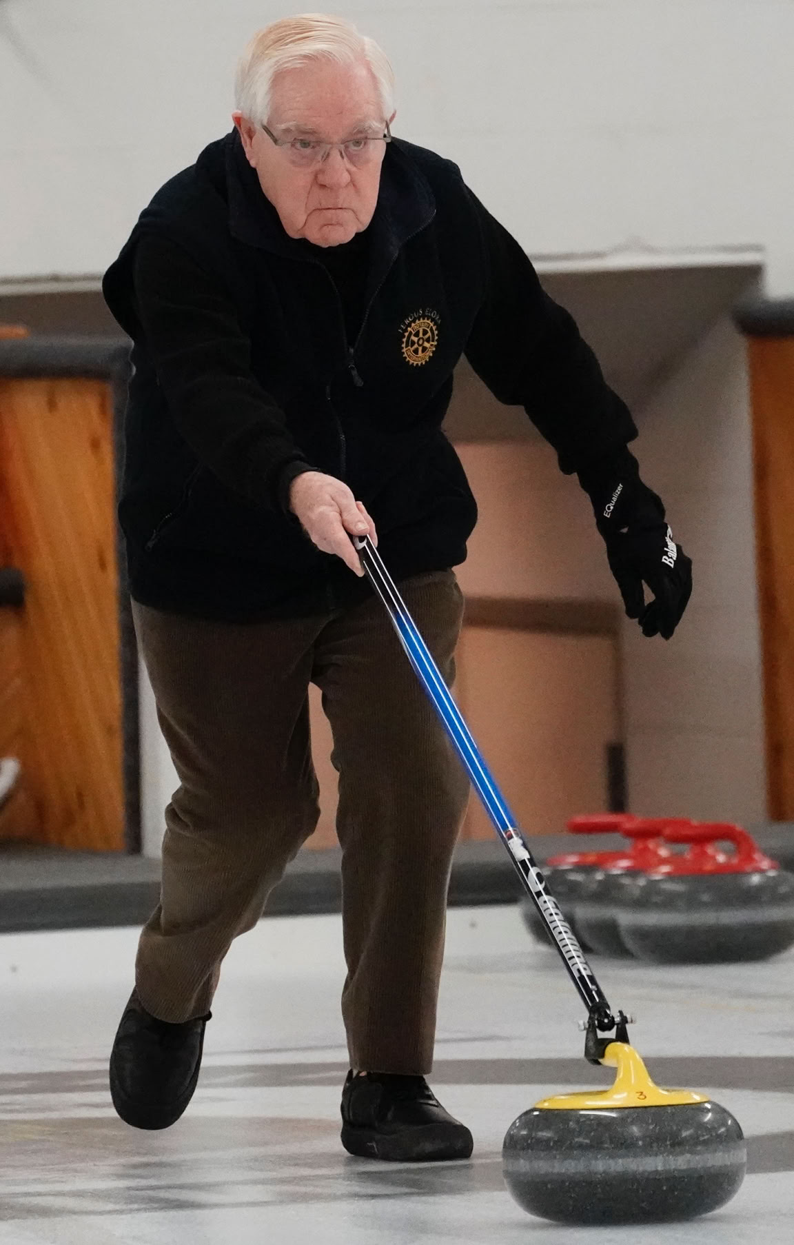 A 2023 Curl For A Cause organizer sweeping in front of the rock.