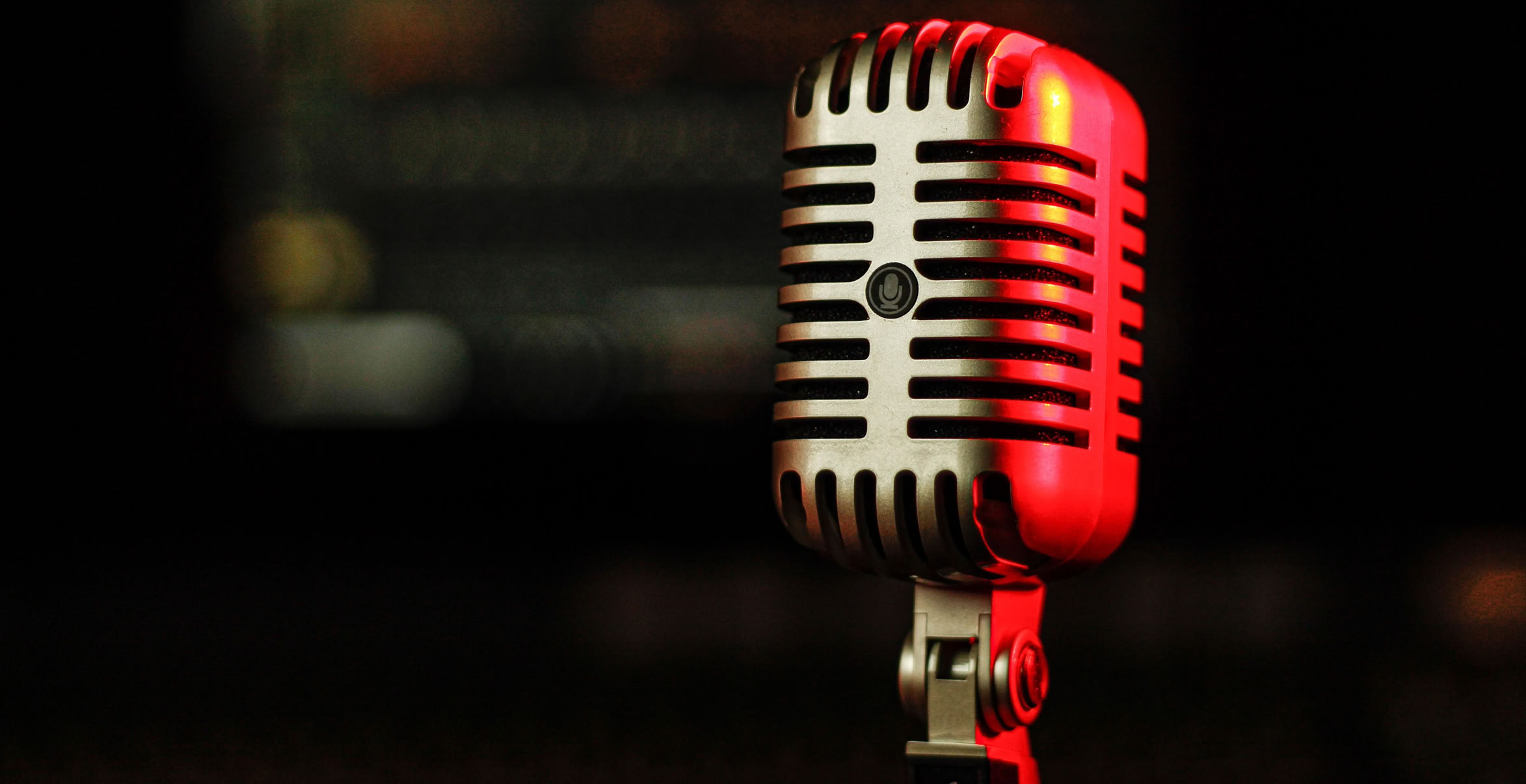 Stainless steel microphone with red light reflecting off it left side and top.